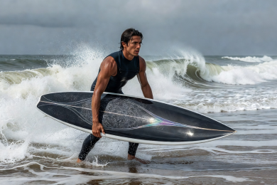 Sleek performance surfboard held by ocean surfer